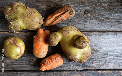 Trendy ugly organic produce  - Several carrots and potatoes lie on a wooden gray table. Сopy space. Top view. Horizontal orientation. Buying imperfect products is a way to deal with food waste