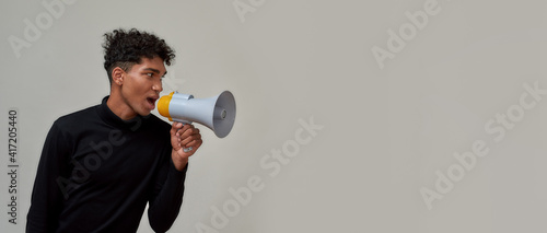 Принти на полотні Stylish young guy with piercing dressed in black looking away and screaming in m