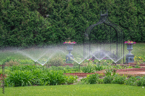 Water sprays from sprinklers in a formal Victorian garden