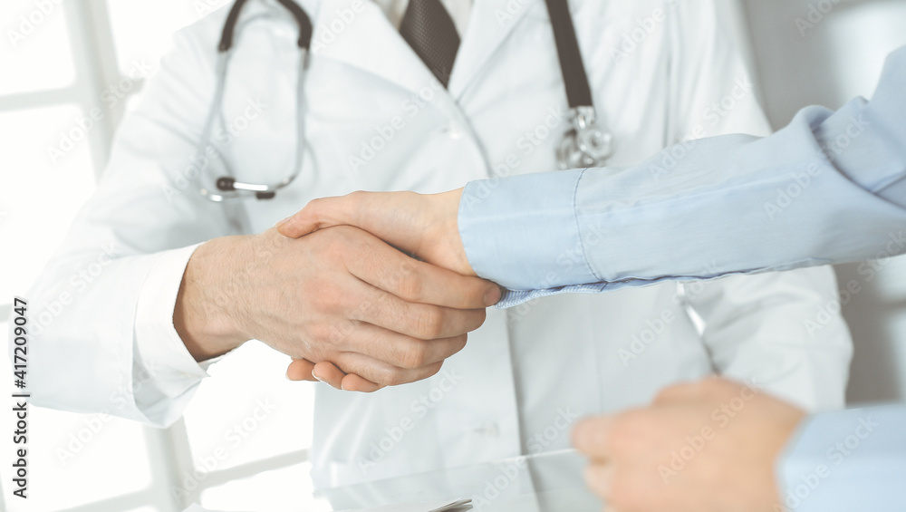 Unknown male doctor and woman-patient discussing current health examination while sitting in clinic and using clipboard. Good medical service in hospital. Medicine concept Unknown male doctor and woman-patient discussing current health examination while sitting in clinic and using clipboard. Good medical service in hospital. Medicine concept