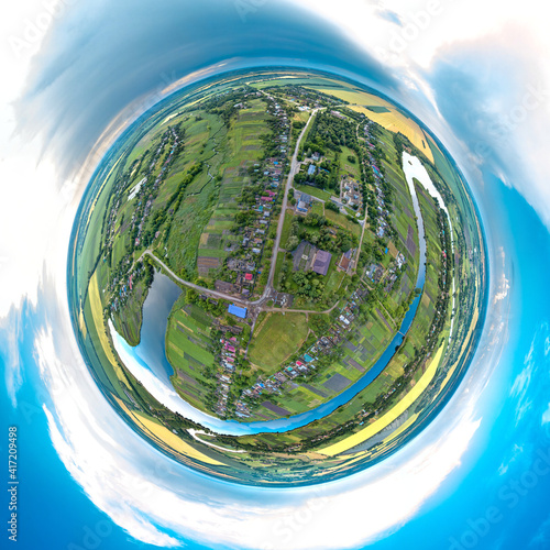 little planet 360-pano - summer landscape of the street of the village of Bratsk surrounded by a blue lake under the sky with clouds among green fields on a summer day