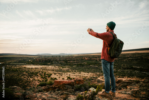 Caucasian male hiking in the wilderness taking images on cellular device 