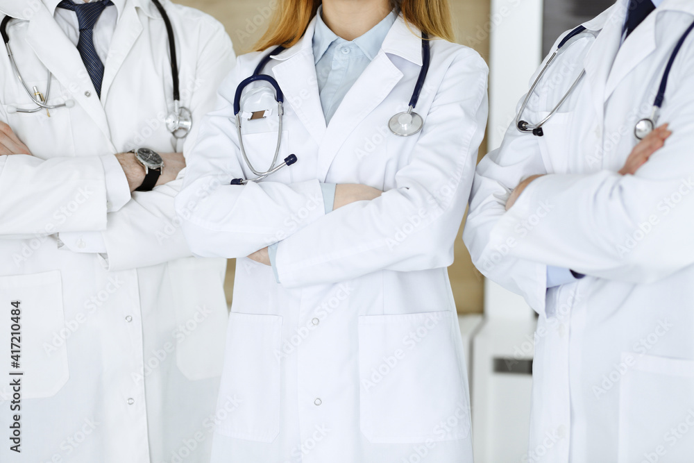 Group of unknown doctors standing as a team with arms crossed in hospital office, close-up. Medical help, insurance in health care and medicine concept Group of unknown doctors standing as a team with arms crossed in hospital office, close-up. Medical help, insurance in health care and medicine concept