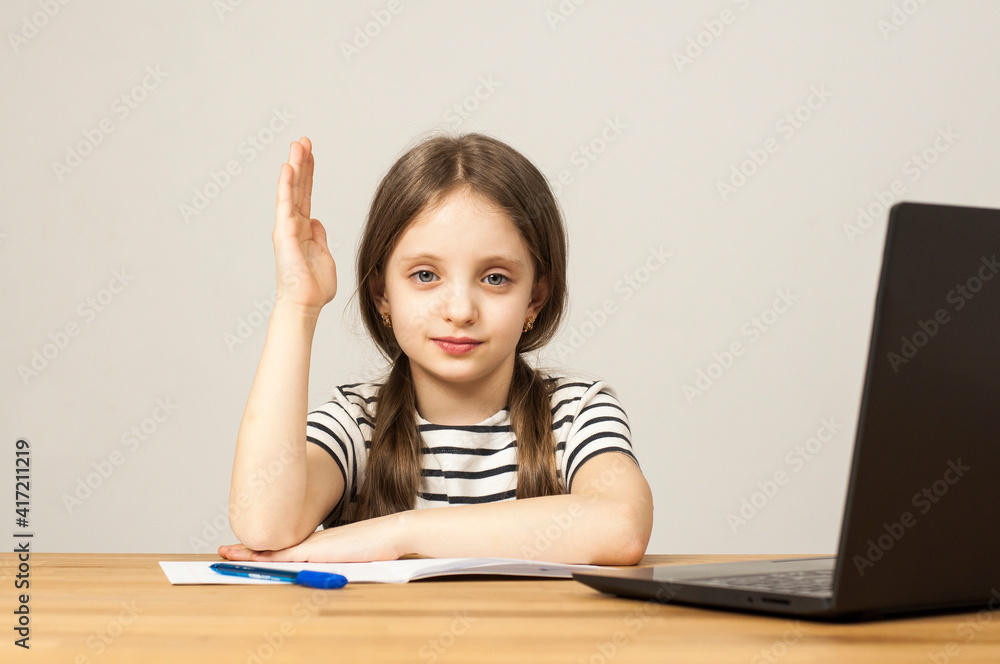 A European girl is sitting at a table doing her homework. Online training through zoom. Distance learning. laptop