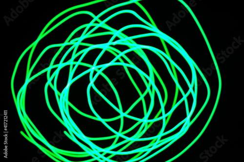 Green abstract background - lines and streaks of light. Blurred, irregular light elements on black background. Green fanciful 3d patterns.