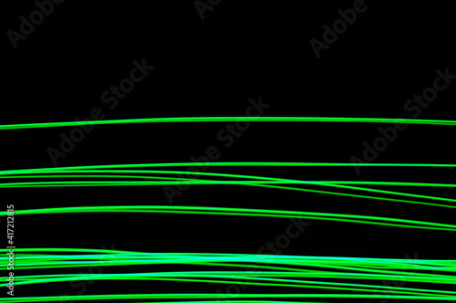 Green thin lines of light on black background. Laser irregular light beams. Luminous, bright threads of green color with high density.