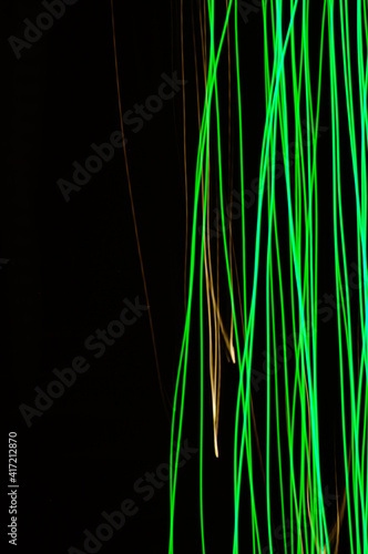 Green thin lines of light on black background. Laser irregular light beams. Luminous, bright threads of green color with high density.