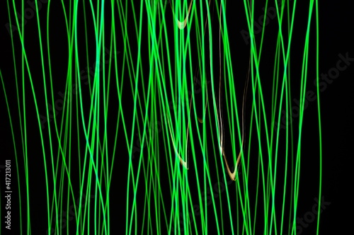 Green thin lines of light on black background. Laser irregular light beams. Luminous, bright threads of green color with high density.