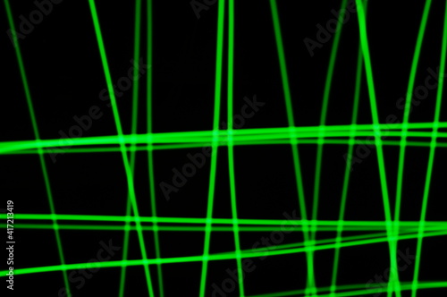 Green thin lines of light on black background. Laser irregular light beams. Luminous, bright threads of green color with high density.