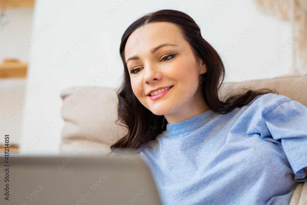 beautiful young woman in pajamas lies at home on the couch with a laptop beautiful young woman in pajamas lies at home on the couch with a laptop
