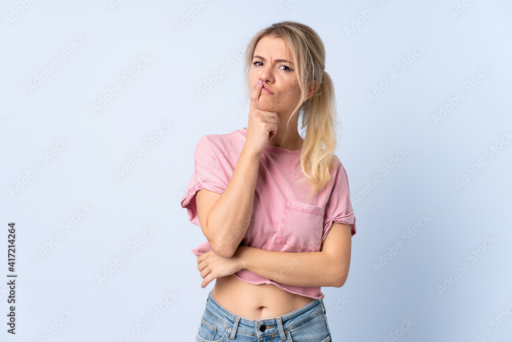 Blonde woman over isolated blue background having doubts while looking up Blonde woman over isolated blue background having doubts while looking up