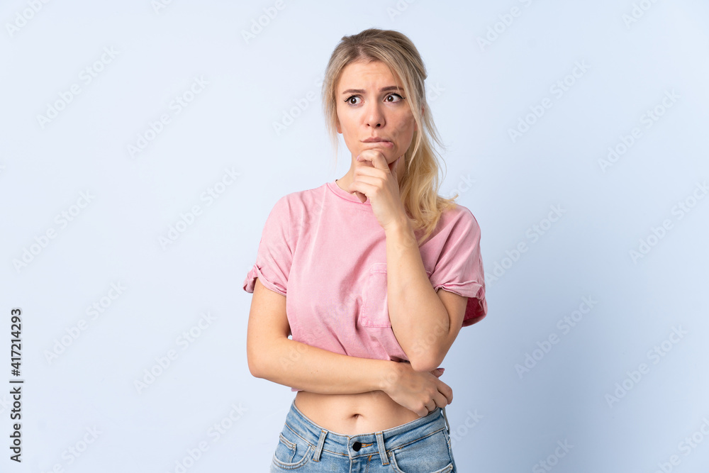 Blonde woman over isolated blue background having doubts and thinking Blonde woman over isolated blue background having doubts and thinking