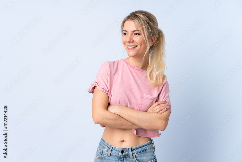 Blonde woman over isolated blue background looking to the side and smiling Blonde woman over isolated blue background looking to the side and smiling