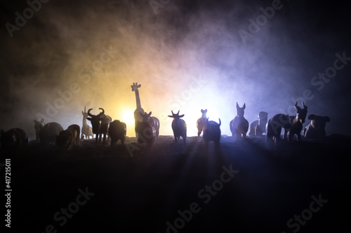 A group of animals are grouped together on a black background with glowing white rays. Animals range from an elephant, zebra, bear and rhino. Use it for a zoo or friends concept. © zef art