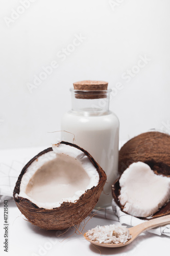 Coconut milk in a glass bottle. Whole and cracked coconut on white background