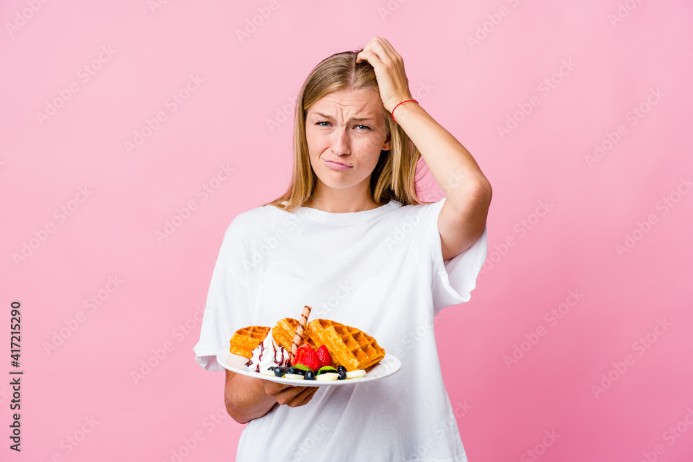 Young russian woman eating a waffle isolated tired and very sleepy keeping hand on head. Young russian woman eating a waffle isolated tired and very sleepy keeping hand on head.