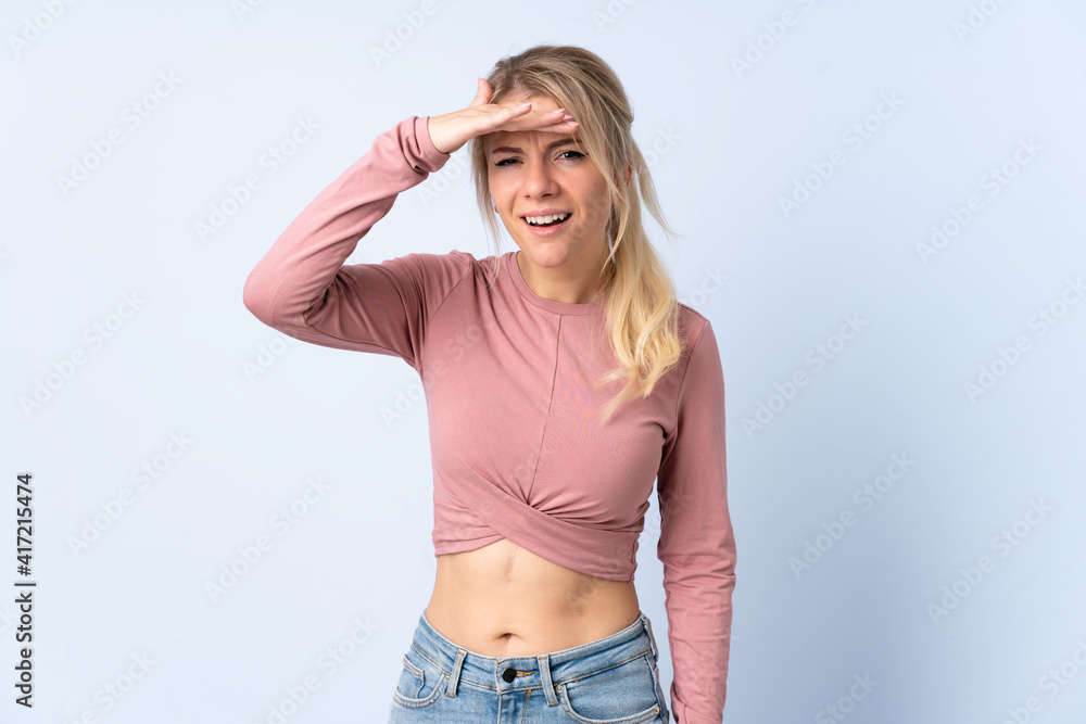 Blonde woman over isolated blue background looking far away with hand to look something Blonde woman over isolated blue background looking far away with hand to look something