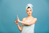 Displeased angry woman against of shaving, holds razor in hand, supports wax depilation, poses half nude, shows bare shoulders, frowns face, isolated over blue background. Women and hygiene concept