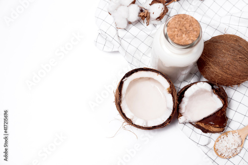 Coconut with coconut oil, water and sugar and coconut flakes on a wooden turquois background