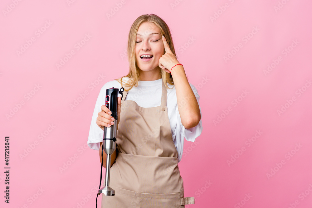 Young russian cook woman holding an electric mixer isolated showing a disappointment gesture with forefinger.