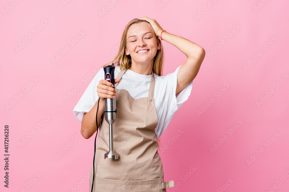 Young russian cook woman holding an electric mixer isolated laughs joyfully keeping hands on head. Happiness concept. Young russian cook woman holding an electric mixer isolated laughs joyfully keeping hands on head. Happiness concept.