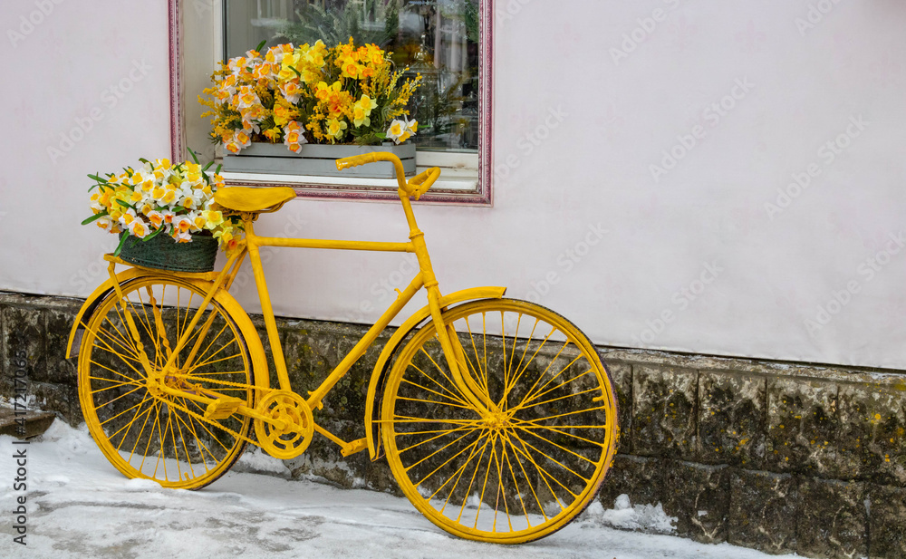Yellow bicycle stands on the background of the wall, under the window of the flower shop, vintage style