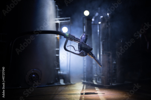 Creative concept. Silhouette of gasoline pistol miniature on dark toned foggy background. Close up. Industrial decorated elements on background.