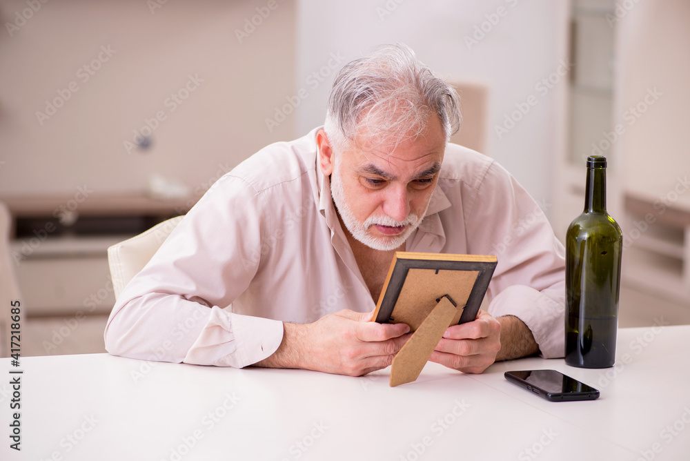Old widower drinking alcohol at home Old widower drinking alcohol at home