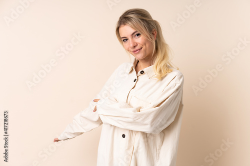 Blonde woman over isolated background extending hands to the side for inviting to come