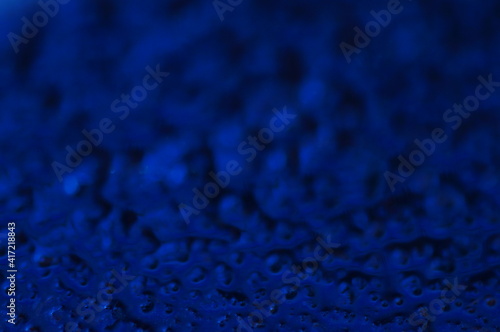 Abstract blue mysterious background. Rough texture in dark light. Oily, oily ooze with bubbles and lumps. Dark uneven background with reflected blue light. 3d illustration with gestural texture.