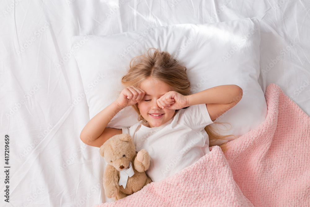little blonde girl sleeping in bed hugging a teddy bear under a pink knitted blanket, space for text little blonde girl sleeping in bed hugging a teddy bear under a pink knitted blanket, space for text