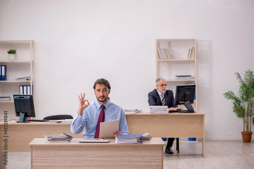 Old male boss and young employee working in the office