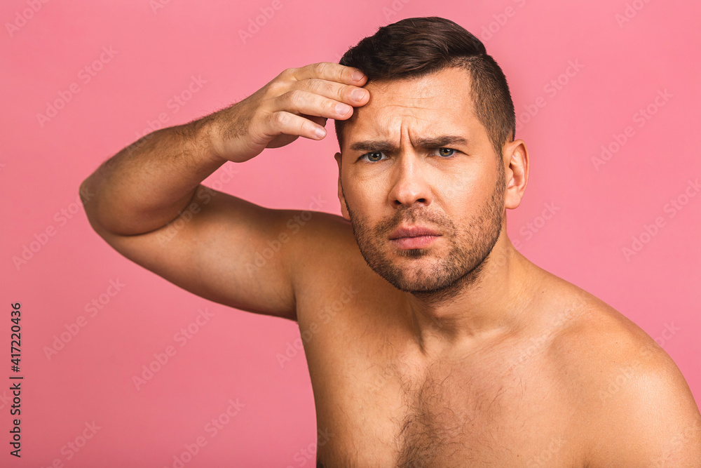 Photo of smiling young beautiful man standing isolated over pink wall background naked. Man's skincare concept in a bathroom. Photo of smiling young beautiful man standing isolated over pink wall background naked. Man's skincare concept in a bathroom.