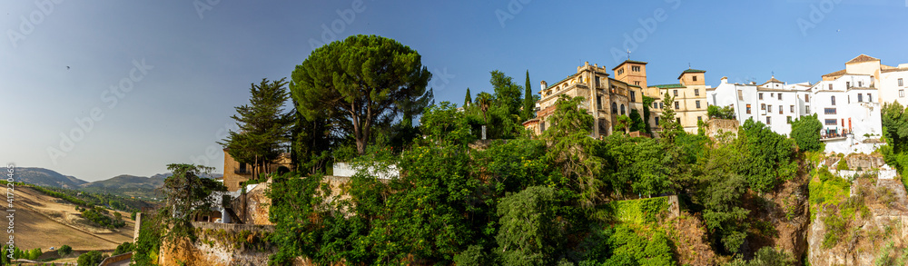 Panoramic view of the touristic town of Ronda, Spain within the Malaga province. This pretty town is located on top of a deep gorge. Image shows the view across the gorge and features old buildings.