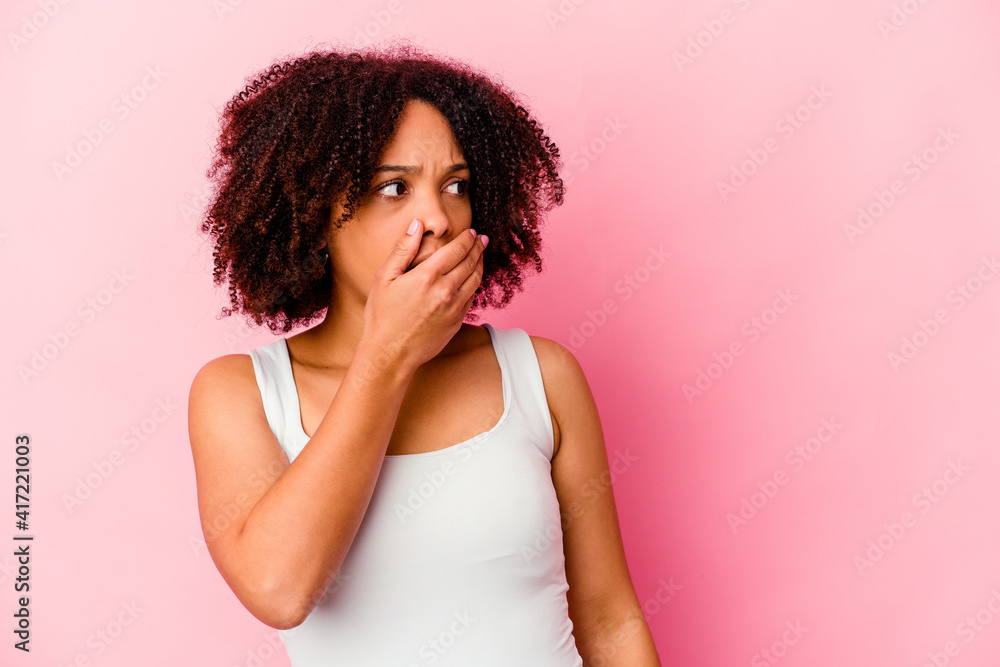 Young african american mixed race woman isolated thoughtful looking to a copy space covering mouth with hand. Young african american mixed race woman isolated thoughtful looking to a copy space covering mouth with hand.