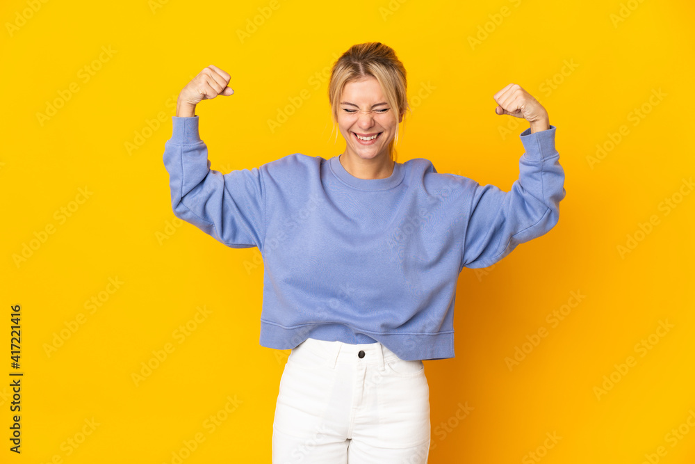 Young Russian woman isolated on yellow background doing strong gesture Young Russian woman isolated on yellow background doing strong gesture