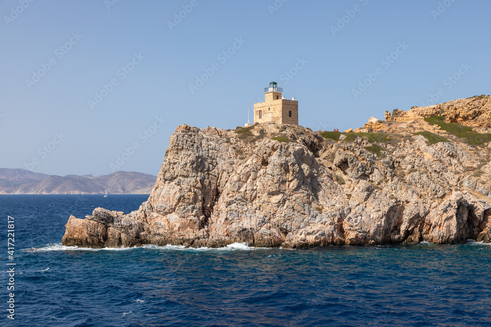 Lighthouse on the rock in the background. Chora , Ios Island, Greece.