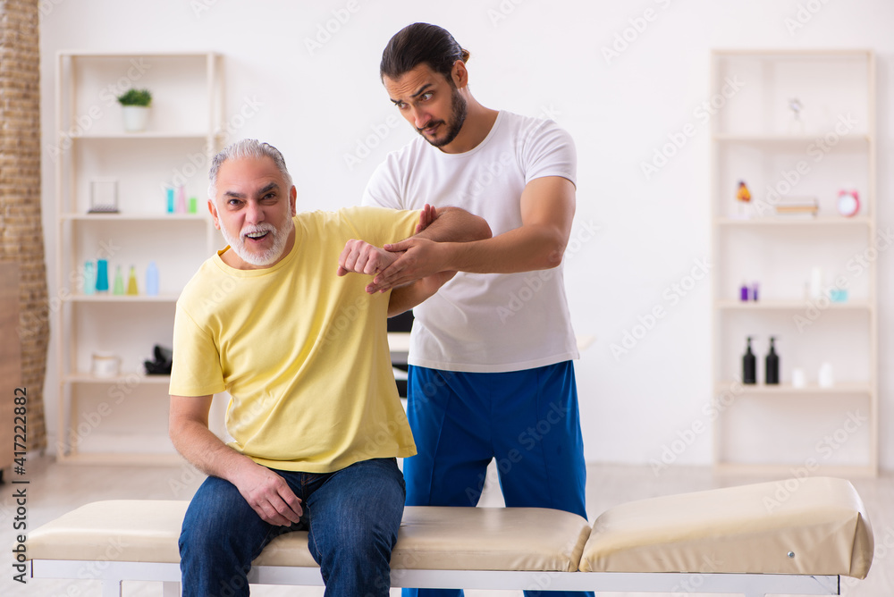 Fototapeta premium Old male patient visiting young male doctor chiropractor