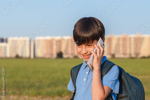 Schoolboy with backpack in his hands mobile phone against the background of the city landscape