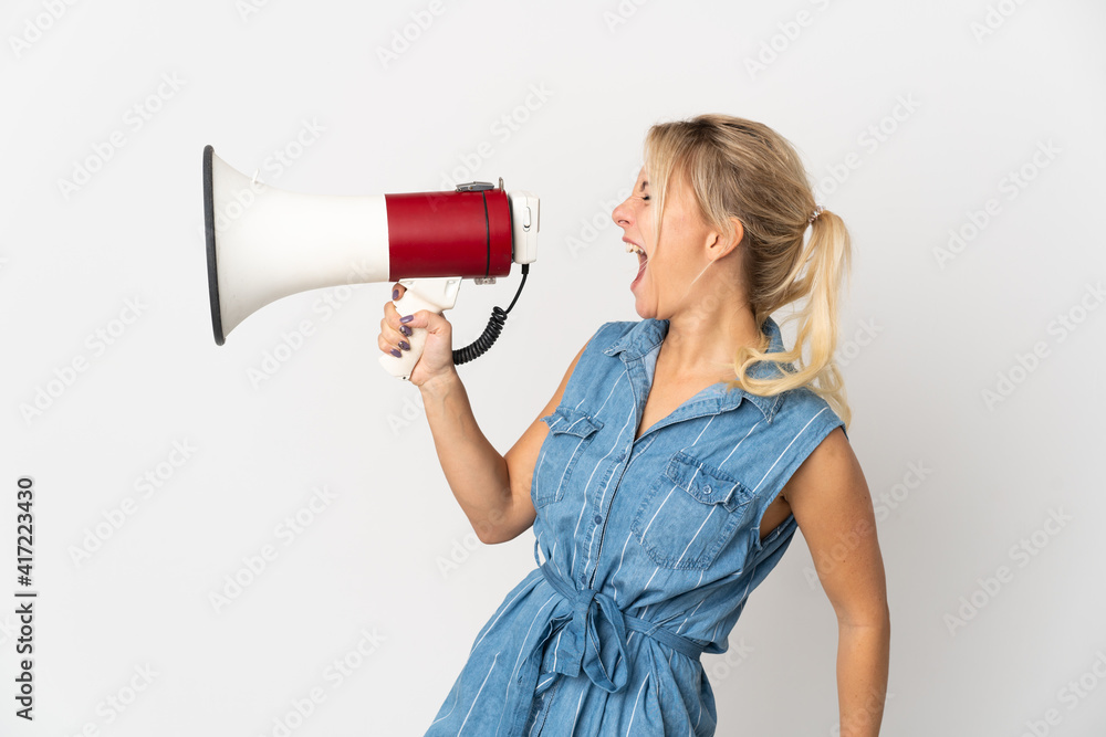 Young Russian woman isolated on white background shouting through a megaphone to announce something in lateral position Young Russian woman isolated on white background shouting through a megaphone to announce something in lateral position