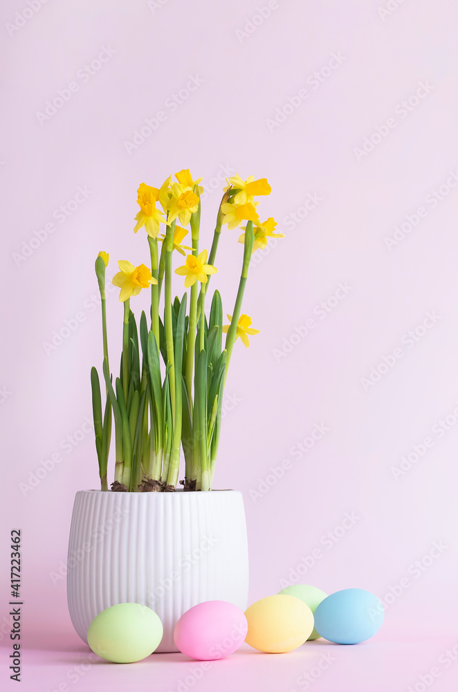 Obraz premium Easter eggs and garden flowers in a pot on the pastel pink background with copu space . Vertical .Gardening team. Happy Easter card .