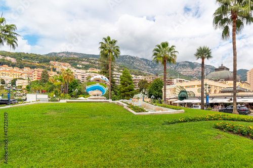 The famous casino is reflected in the large round mirror in the casino gardens with the city and mountains behind in the coastal resort city of Monte Carlo, Monaco.