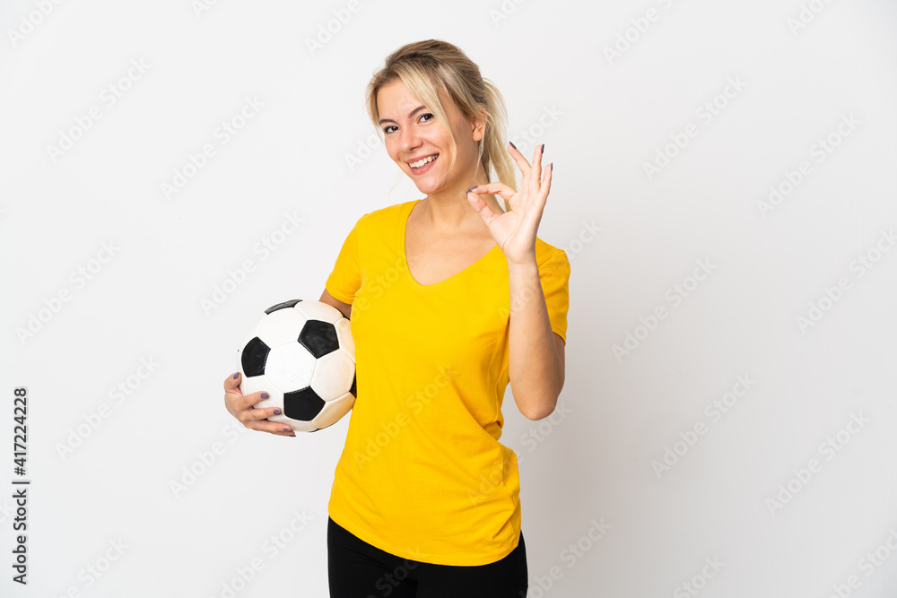 Young Russian woman isolated on white background with soccer ball and making OK sign Young Russian woman isolated on white background with soccer ball and making OK sign