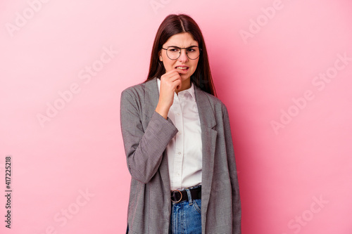 Young caucasian business woman isolated on pink background biting fingernails, nervous and very anxious.