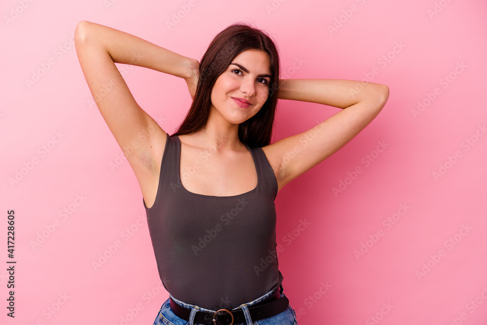Young caucasian woman isolated on pink background feeling confident, with hands behind the head. Young caucasian woman isolated on pink background feeling confident, with hands behind the head.
