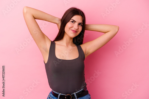 Young caucasian woman isolated on pink background feeling confident, with hands behind the head. © Asier