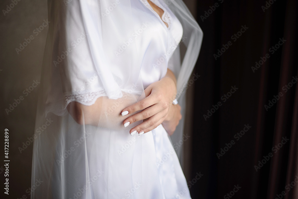 The bride in a dressing gown hugs herself.