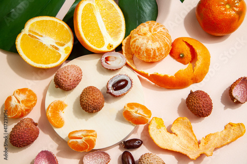 Tasty lychees and oranges arranged on pink table