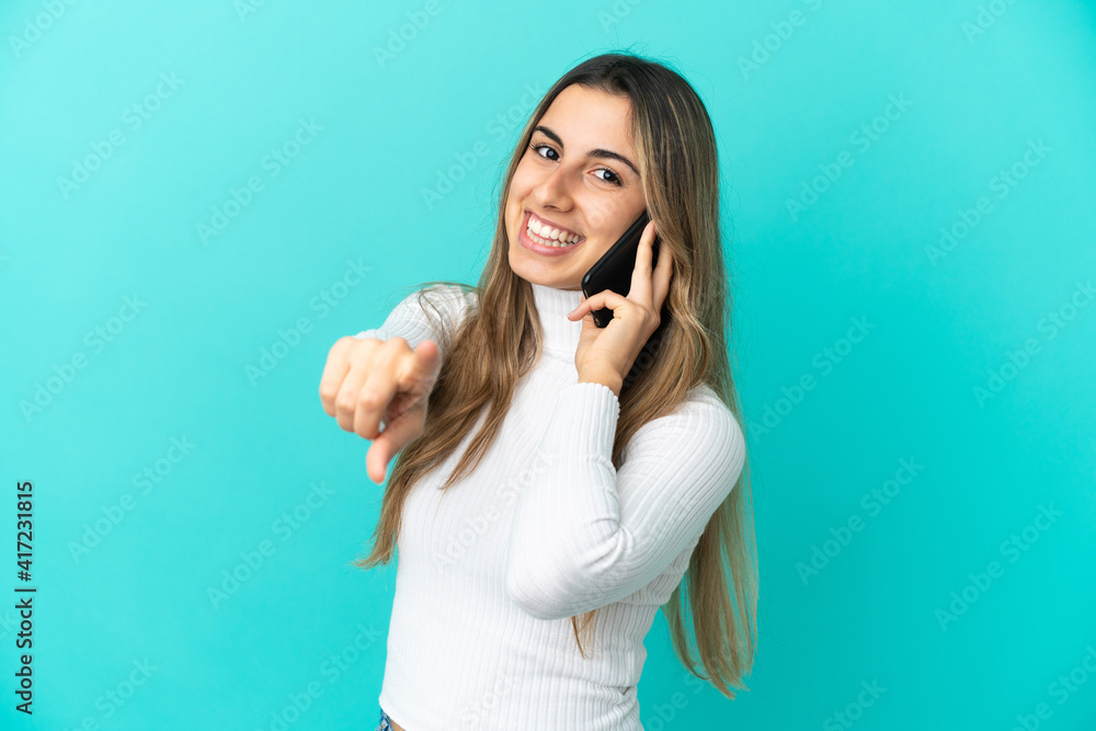 Young caucasian woman using mobile phone isolated on blue background pointing front with happy expression Young caucasian woman using mobile phone isolated on blue background pointing front with happy expression