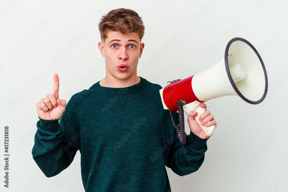 Young caucasian man holding a megaphone isolated on white background having some great idea, concept of creativity. Young caucasian man holding a megaphone isolated on white background having some great idea, concept of creativity.